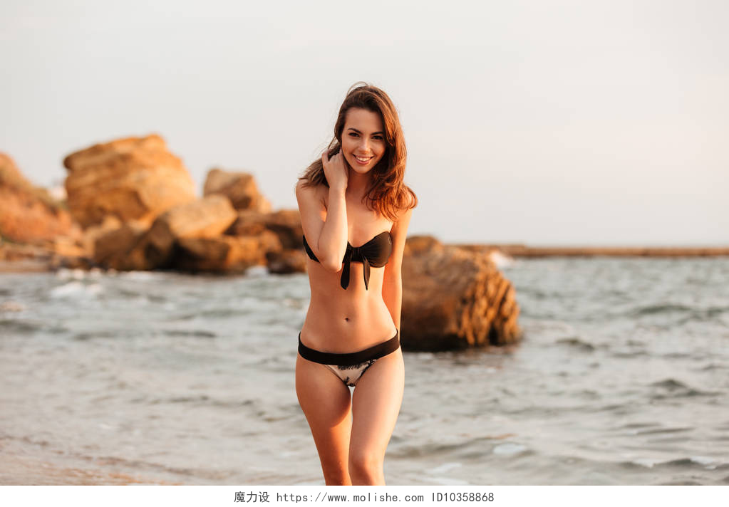 穿着比基尼在海滩玩耍的美女微笑比基尼在海滩上行走的黑发的女人